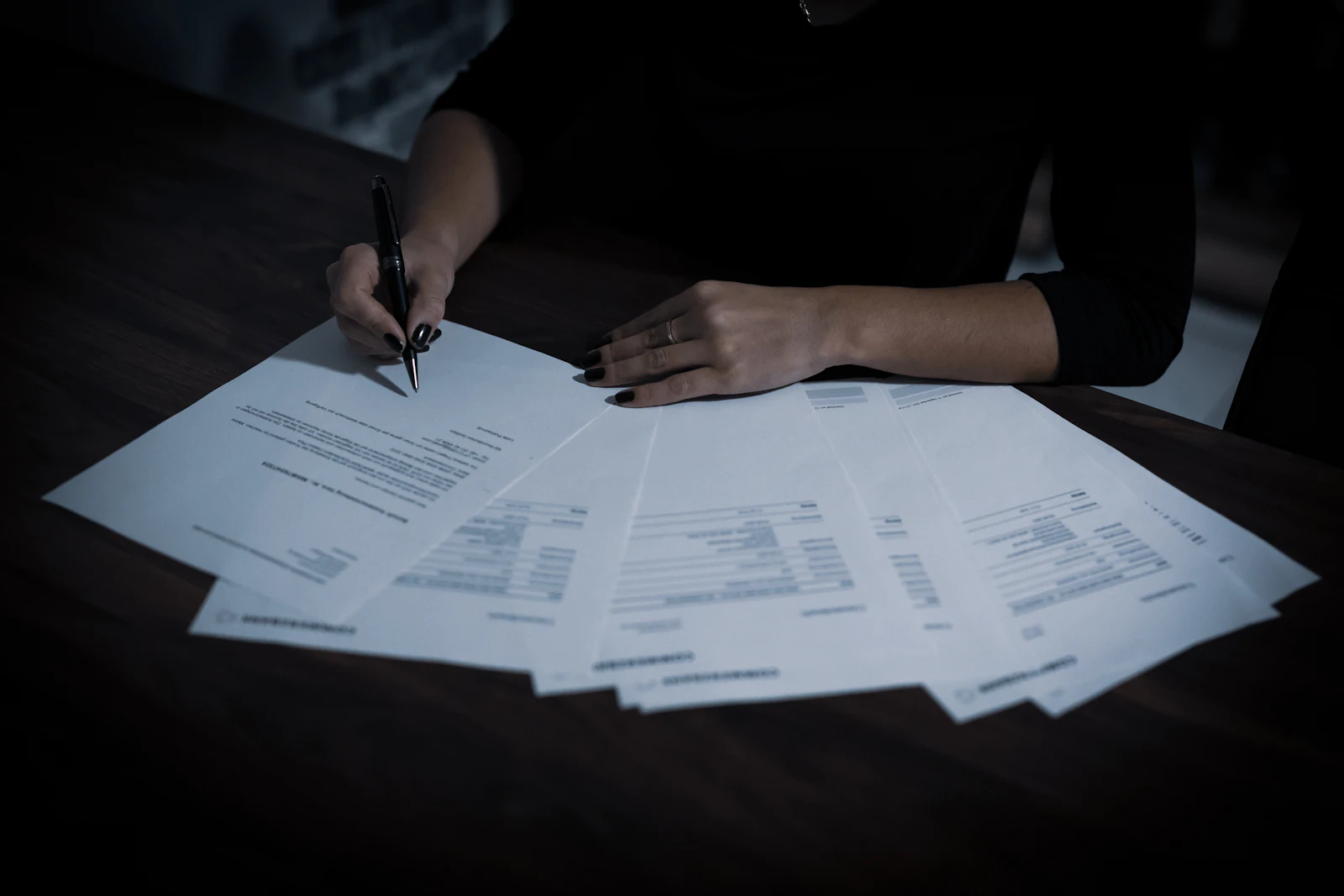 A woman signing papers at a table covered in documents